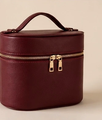 Three-quarter view of the closed burgundy vanity bag.